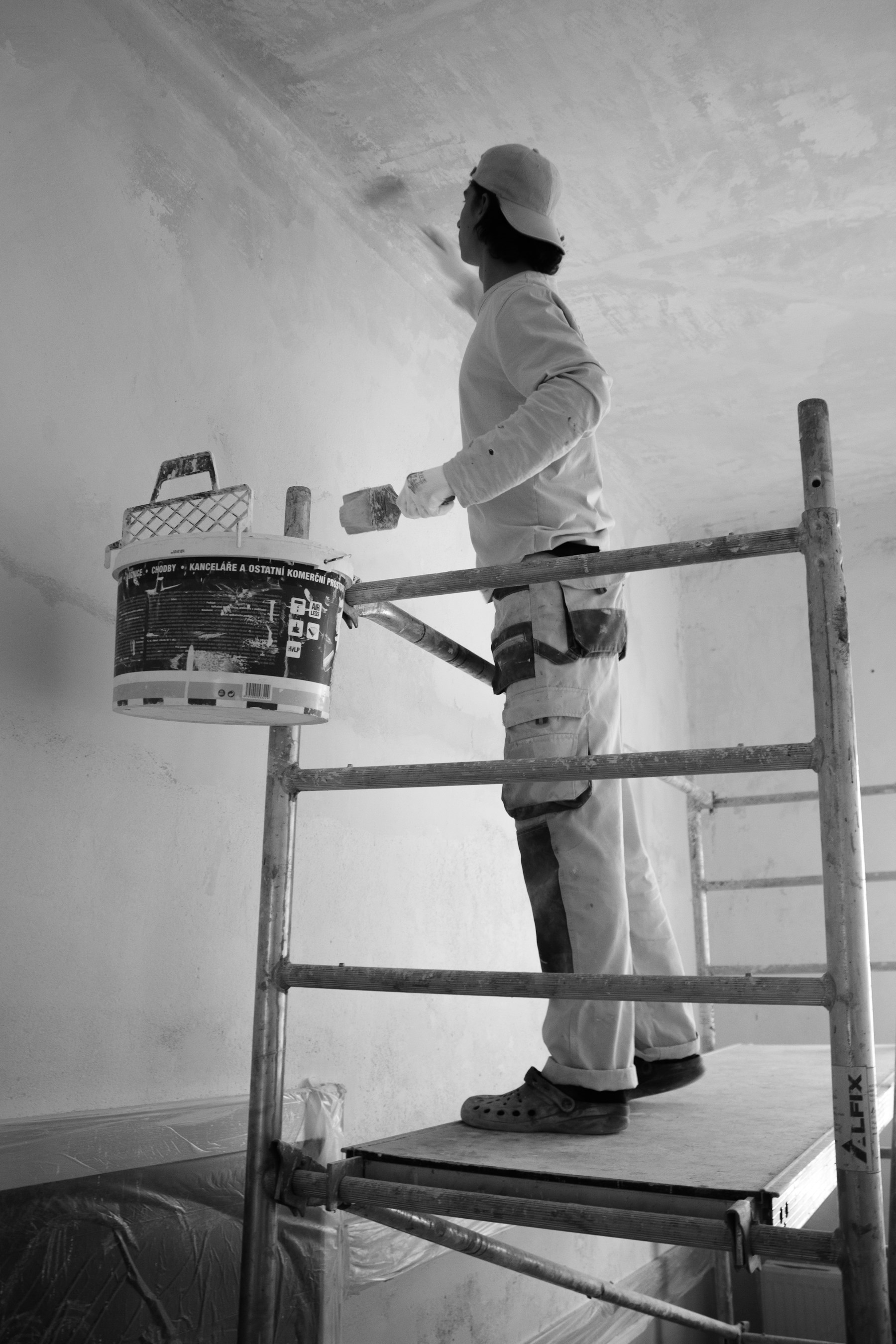 Painter carefully preparing a tall interior wall before repainting